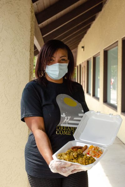 volunteer showing off a plate from the caribbean delish fundraiser